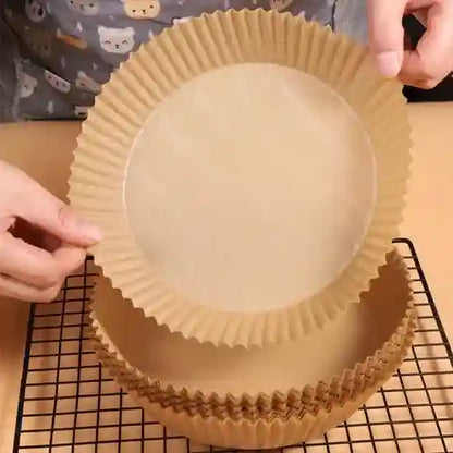 Person preparing a round baking pan with a brown paper lining on a cooling rack.