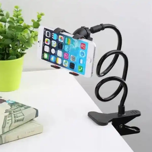 Phone holder with a smartphone on a white surface with a plant in the background