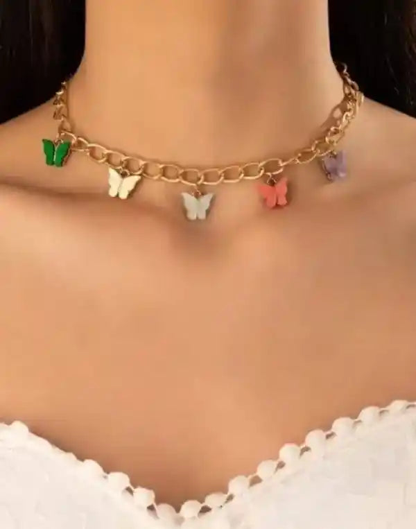 Gold chain necklace with colorful butterfly charms on a person wearing a white top.