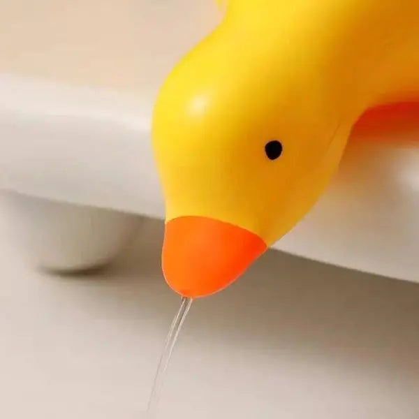 Yellow rubber duck with water flowing from its beak on a white background