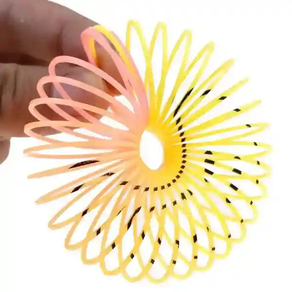 Yellow and pink slinky toy held by a hand on a white background