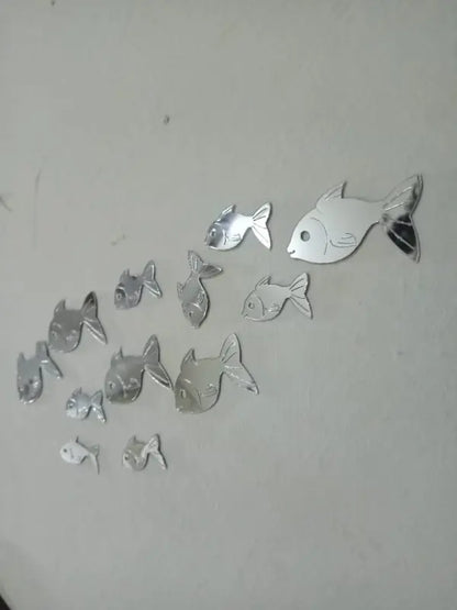 Set of silver fish-shaped mirror stickers on a white background