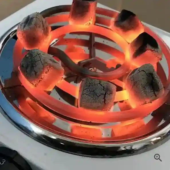 Gas stove burner with glowing red-hot coils and blackened grate.