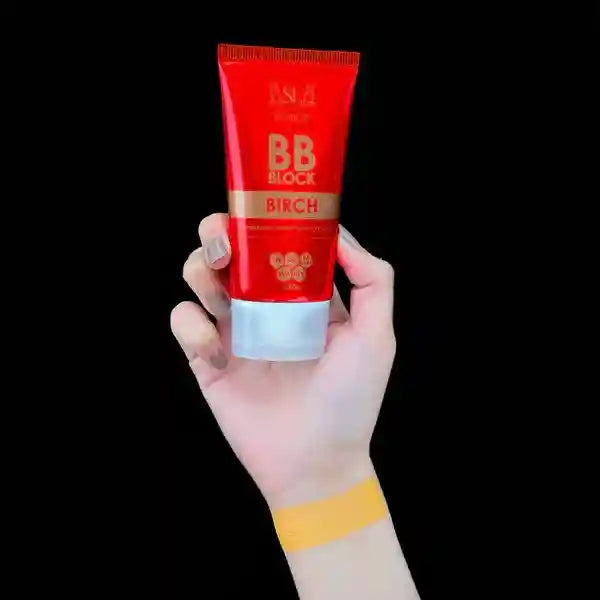 Red BB cream tube held by a hand against a black background