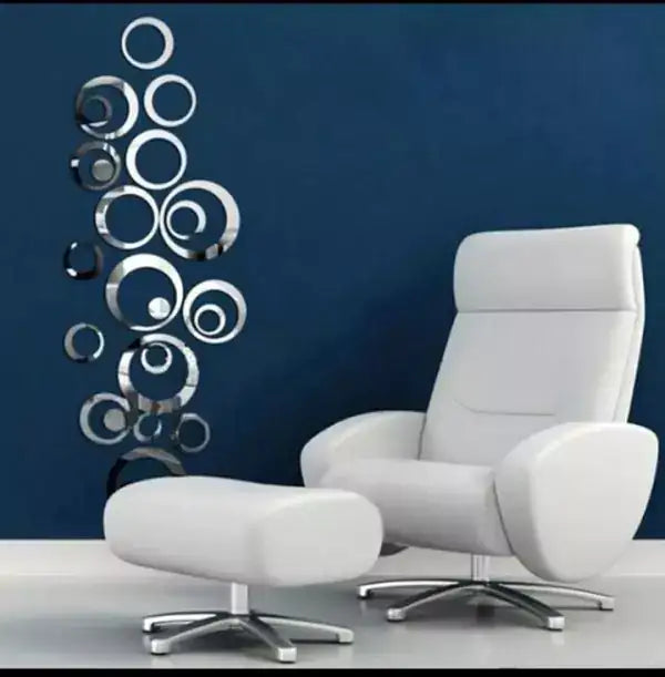 White armchair and ottoman with decorative wall mirrors on a blue wall.
