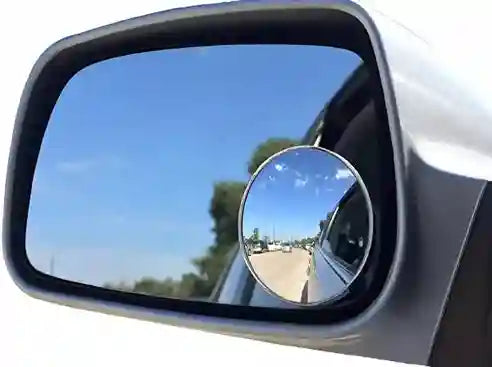Car side mirror with a small round convex mirror attached, showing a clear view of the road.