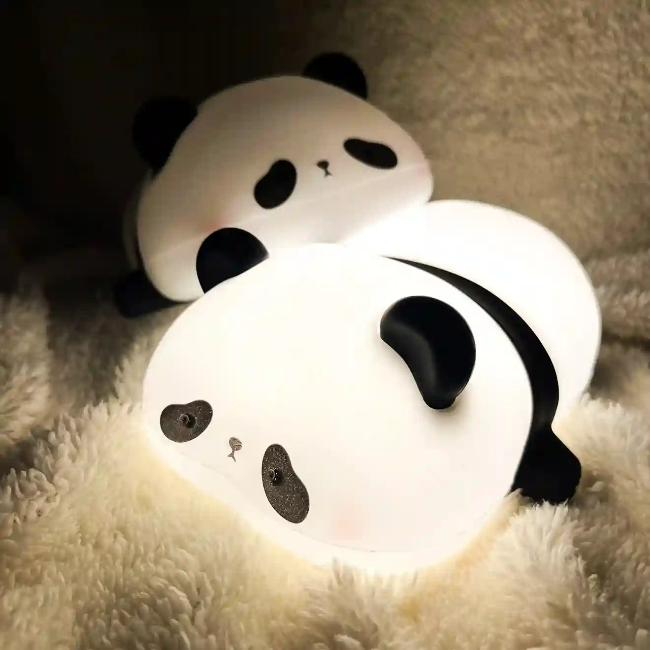 Two panda-shaped night lights on a soft surface