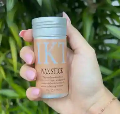Hand holding a wax stick with 'IKT' branding against a green leafy background