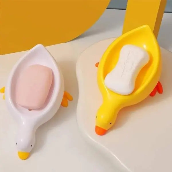 Two duck-shaped soap holders with soap bars on a light surface.