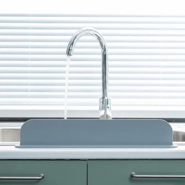 Gray kitchen sink with a chrome faucet against a white window blind background