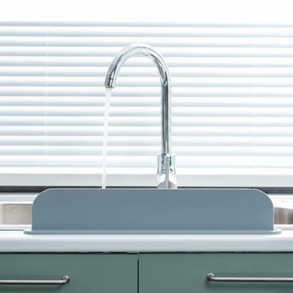 Gray kitchen sink with a chrome faucet against a white window blind background