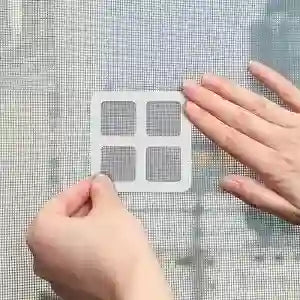 Hands holding a small grid-like tool over a textured surface