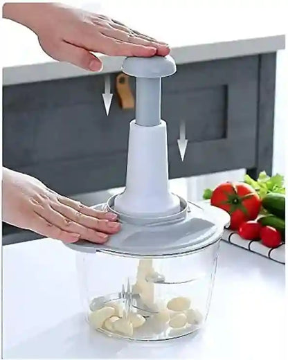 Hand using a garlic press with a container of chopped garlic on a kitchen counter.