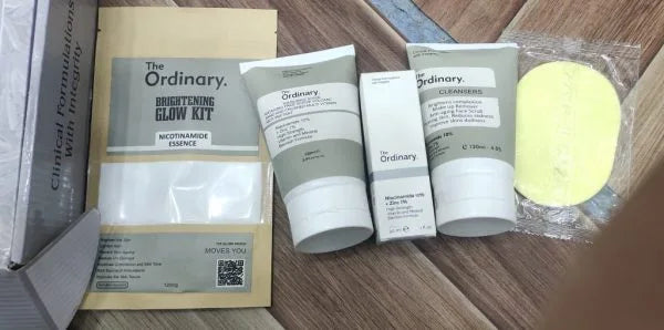 The Ordinary skincare product set with tubes, a sponge, and packaging on a wooden surface.