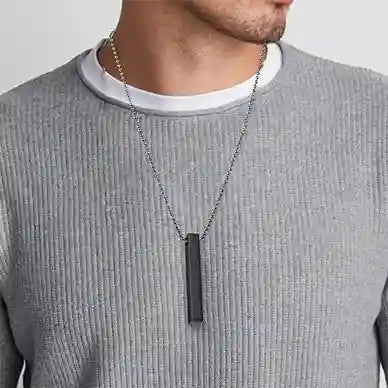 Person wearing a gray textured sweater with a necklace featuring a rectangular pendant.