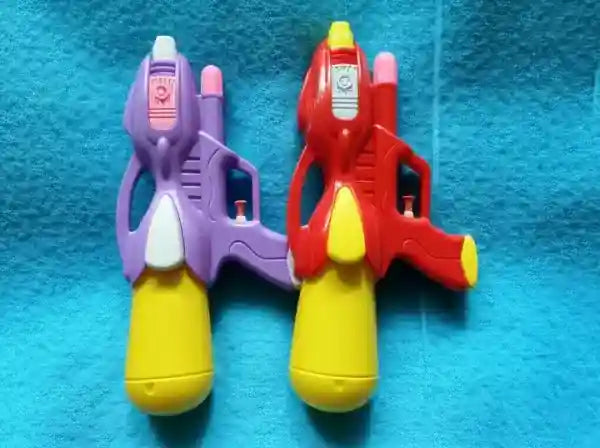 Two toy water guns, one purple and one red with yellow nozzles, on a blue textured surface.