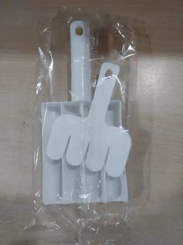 Set of white kitchen utensils including a brush and spatulas in clear packaging on a wooden surface.