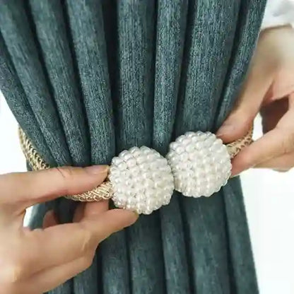Curtain tieback with pearl design being used to hold back a curtain.