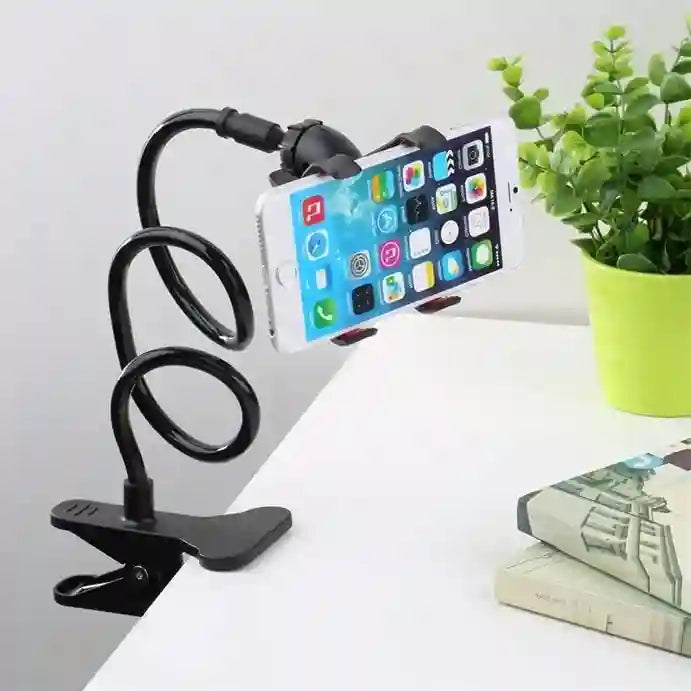 Phone holder with a smartphone on a white surface with a plant in the background