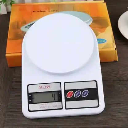 Digital kitchen scale on a wooden surface with an orange box in the background