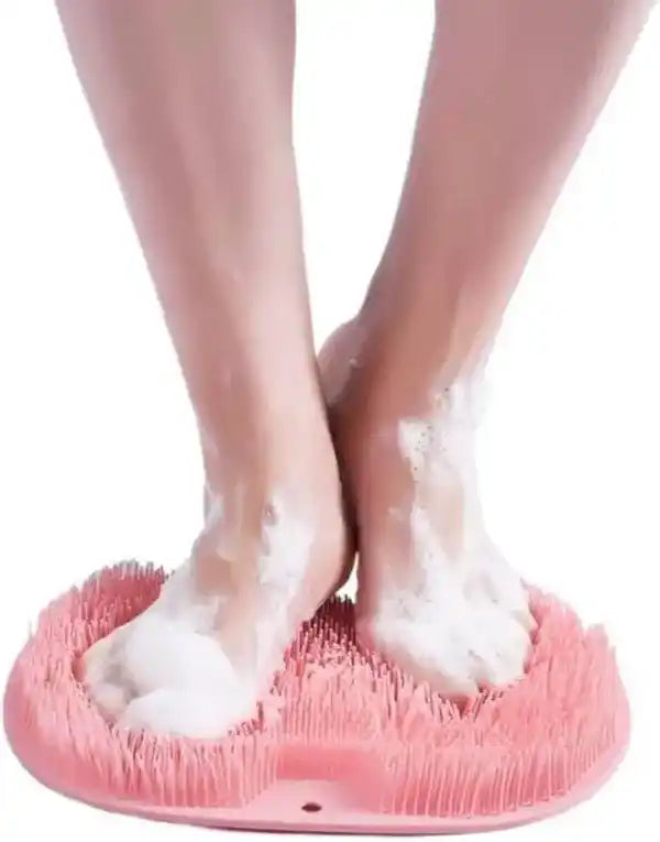 Person using a pink foot scrubber with soapy feet on a white background