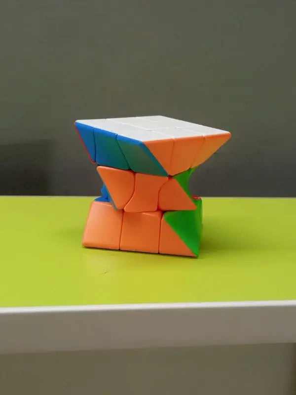 Colorful twisted cube puzzle on a green surface with a gray background