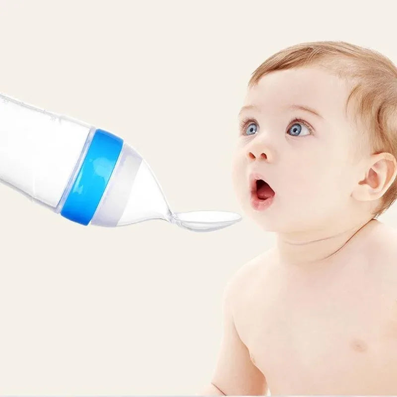 Baby looking at a blue and white bottle with a droplet on a light beige background