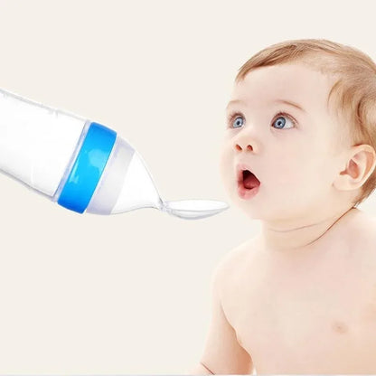 Baby looking at a blue and white bottle with a droplet on a light beige background