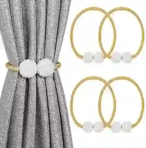 Gold curtain rings with white pom-poms on a gray curtain