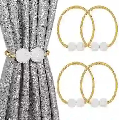 Gold curtain rings with white pom-poms on a gray curtain