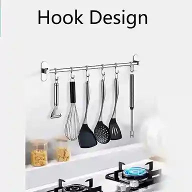 Kitchen utensils hanging on a wall-mounted hook rack with a stove and countertop in the background.