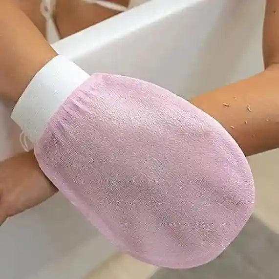 Pink exfoliating glove on a person's hand with a white background