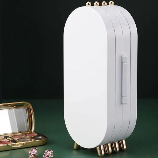White jewelry box with gold accents on a green surface