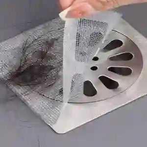 Person using a tool to clear a clogged drain with hair and debris.