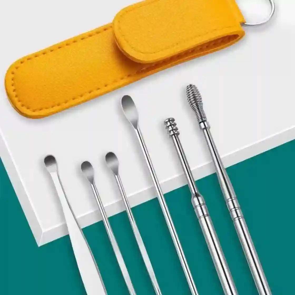 A set of stainless steel ear cleaning tools arranged on a white surface with a teal background, alongside a bright yellow felt carrying pouch and key ring.