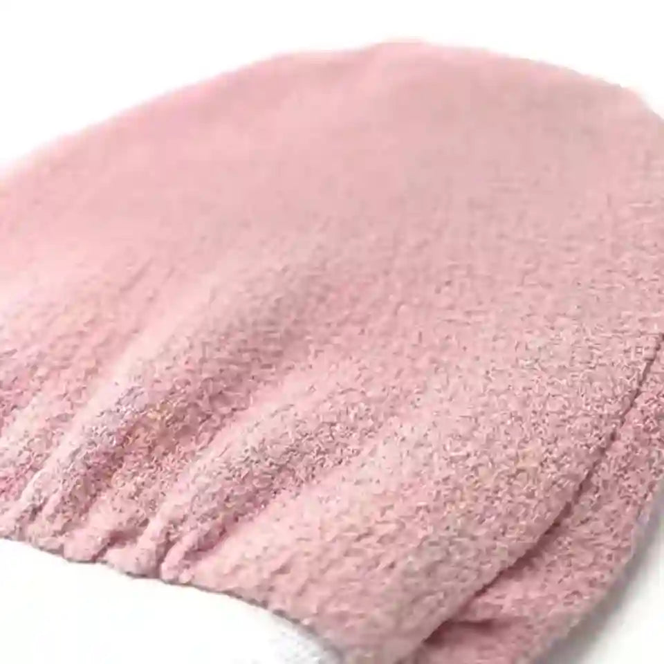 A close-up of a soft pink textured fabric item, likely a beanie or knit hat, folded on a white background.