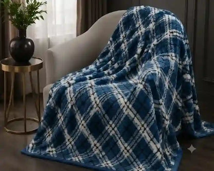 A plush blue and white plaid throw blanket draped over a modern beige armchair in a cozy living room setting.