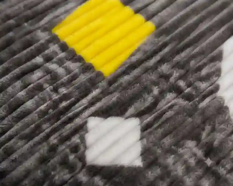 Close-up of a textured gray ribbed fabric with a yellow diamond and white square pattern.
