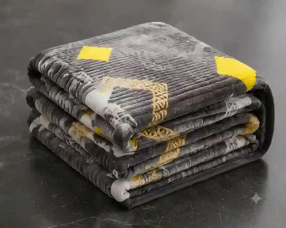 A stack of four folded ribbed bath mats in a dark gray and black pattern with yellow and white accents, resting on a dark gray surface.