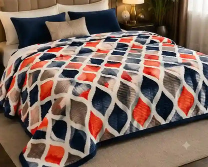 A cozy bed in a bedroom setting featuring a textured blanket with a geometric diamond pattern in navy blue, orange, gray, and white.