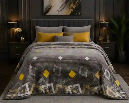 A gray textured blanket with yellow and white geometric diamond and square patterns is styled on a bed in a modern, dark-themed bedroom setting.