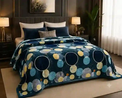 A bed dressed in a dark blue patterned blanket with large circles in navy, light blue, yellow, and gray, styled in a modern bedroom setting.