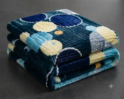 A folded plush blanket with a blue, navy, light blue, and cream floral pattern, displayed on a dark gray surface.
