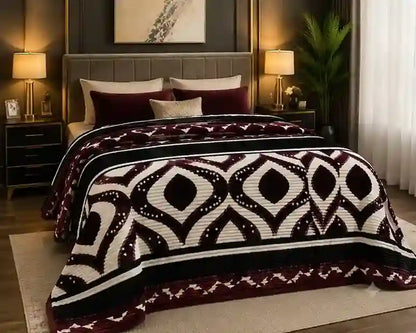 A bed dressed in a textured knit blanket featuring a bold geometric diamond pattern in deep burgundy, cream, and black, styled in a modern bedroom setting.