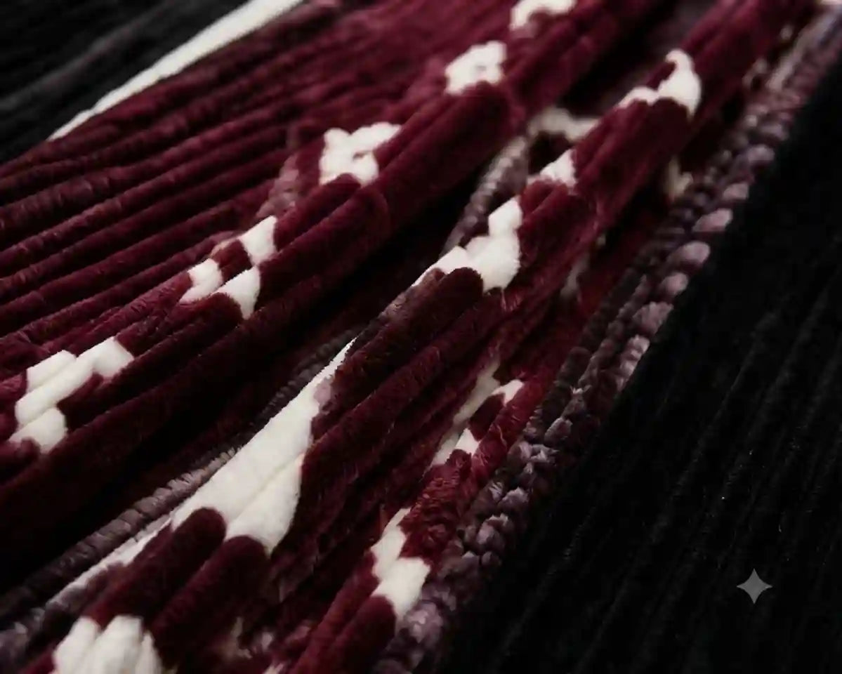 A close-up of a plush velvet textile with a pattern of deep burgundy and white stripes, layered over a black ribbed velvet background.