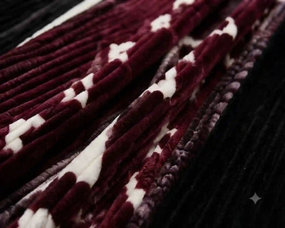 A close-up of a plush velvet textile with a pattern of deep burgundy and white stripes, layered over a black ribbed velvet background.