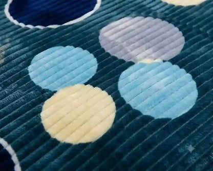 Close-up of a textured fabric featuring a pattern of large polka dots in light blue, pale lavender, and cream on a dark teal corduroy background.