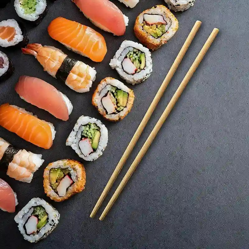 Assorted sushi pieces with chopsticks on a dark surface