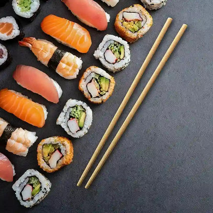 Assorted sushi pieces with chopsticks on a dark surface