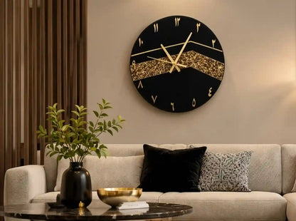 A round black wall clock with gold Roman numerals and a glittery gold horizontal band, mounted above a beige sofa in a modern living room setting.